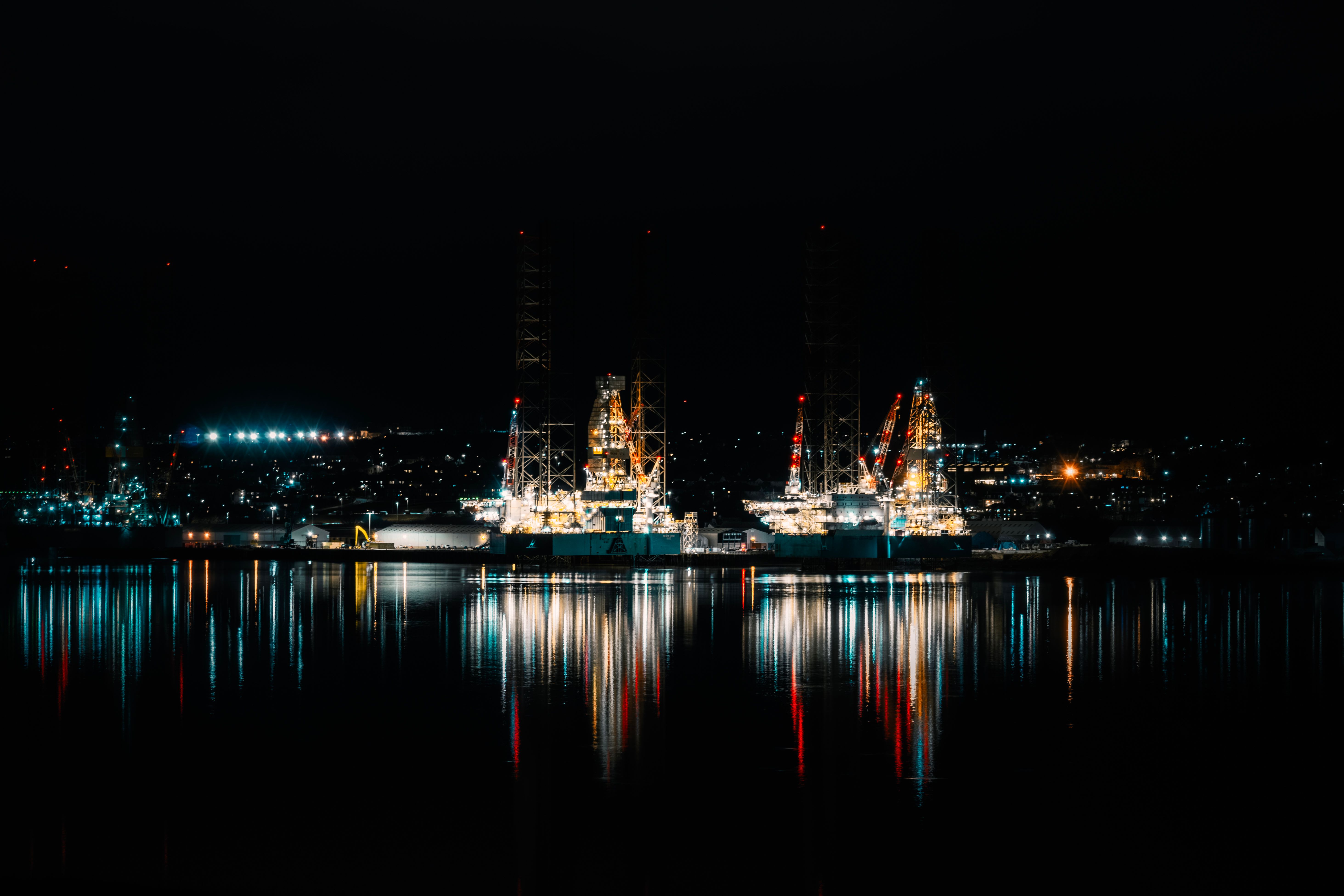 Offshore drilling installations illuminated at night across calm water